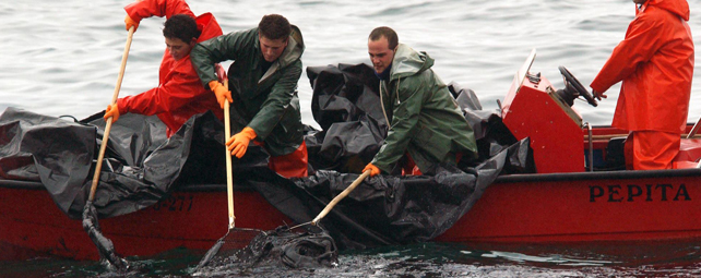 Pescadores recogen fuel frente a la costa de Aguiño en diciembre de 2002. AFP