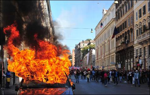 Un coche arde en la manifestación de Roma, Italia. Decenas de miles de personas han marchado por las calles de la capital italiana.-
