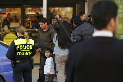 Una agente identifica a inmigrantes en el barrio de Lavapiés (Madrid).-