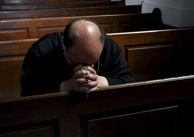 Un sacerdote reza, rosario en mano, en una iglesia de La Haya (Países Bajos).-