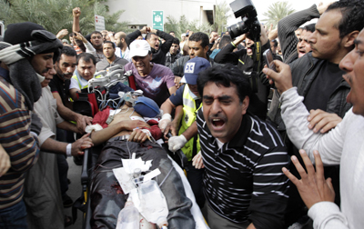 Manifestantes antigubernamentales acompañan, ayer en Manama, a uno de los heridos en el ataque de las fuerzas de seguridad.