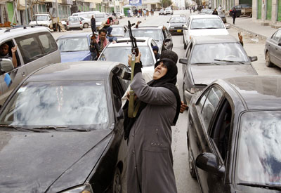 Una mujer dispara un AK-47 para celebrar la noticia de que había comenzado la operación internacional contra las tropas de Gadafi en Bengasi. - REUTERS