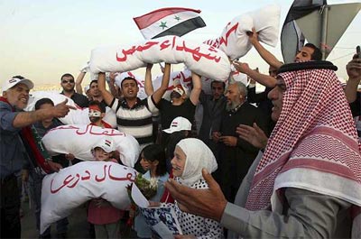 Un grupo de sirios con cadáveres de pega, envueltos en tela, grita consignas contra el presidente sirio Bachar al Asad. -