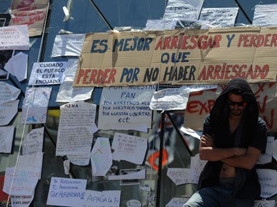 Uno de los participantes en la movilización junto a varios carteles situado en la Puerta del Sol de Madrid. fernando sánchez