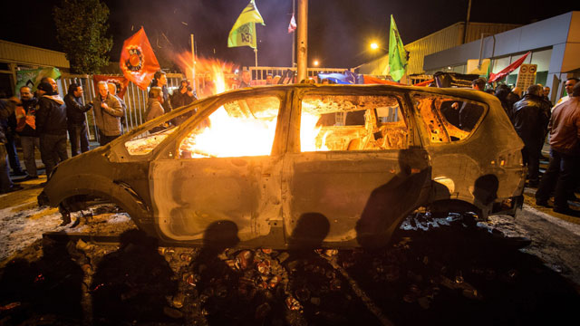 Un auto Ford arde en llamas durante la protesta del jueves en la fábrica de Genk.