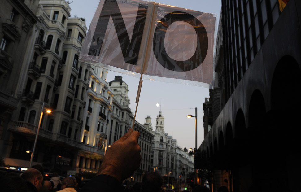 Un manifestante, sostiene una pancarta con la palabra 'No'.