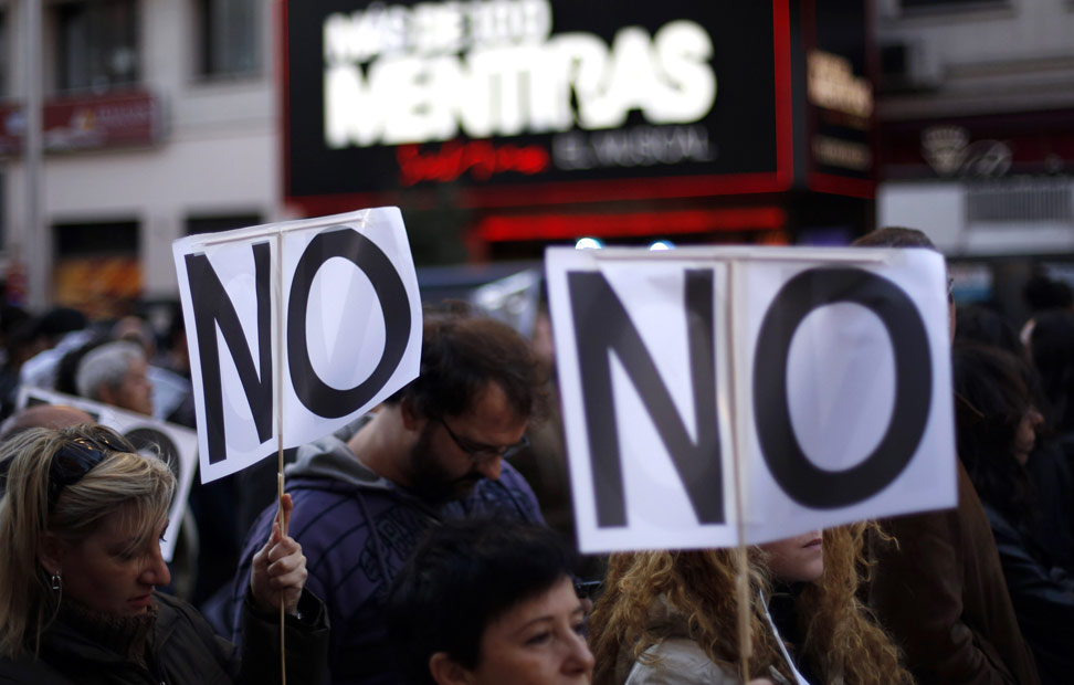 Dos pancartas con la inscripción 'No', con un cartel de fondo del musical 'Más de 100 mentiras', que se anuncia en la madrileña Gran Vía.