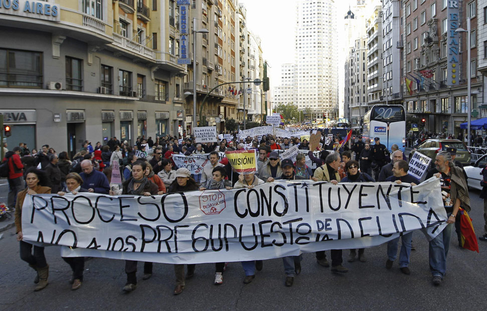 Varias personas portan una pancarta a su paso por la madrileña calle de Gran Vía durante la manifestación 'no comunicada' convocada esta vez contra los presupuestos generales del Estado.
