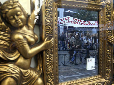 Un grupo de periodistas griegos, reflejado en un espejo de una tienda de antigüedades, protesta en contra de las nuevas medidas de austeridad.  EFE/Orestis Panagiotou