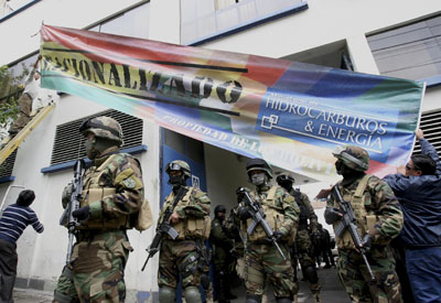 Soldados bolivianos a la entrada de la planta de Electropaz, filial de Iberdrola, donde dos operarios cuelgan el cartel de 'nacionalizada'.
