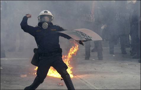 Un policía antidisturbios lanza una piedra contra las manifestantes delante del Parlamento.