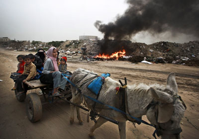 Una familia palestina circula por un vertedero en un carro tirado por un burro.