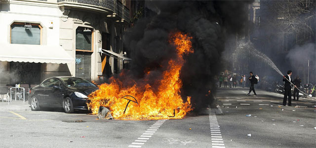 Un coche y diversos contenedores arden esta tarde durante los incidentes registrados en la confluencia de las calles Diputación y Balmes de Barcelona. EFE