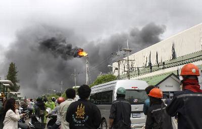 Fotografía facilitada hoy de trabajadores de una fábrica observan el fuego causado por una explosión en en una fábrica petroquímica situada Map Ta Phut al sur de Tailandia.