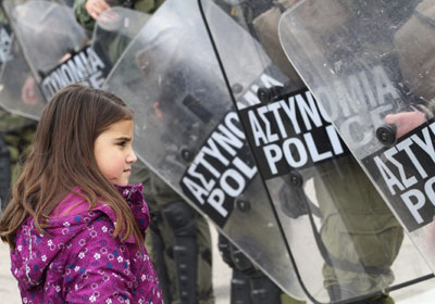 Una menor observa a los antidisturbios que hacen guardia frente al Parlamento en Atenas.