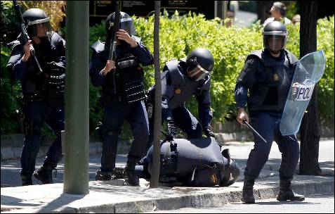 Un policía herido en posición de defensa, mientras es protegido por otros agentes - EFE