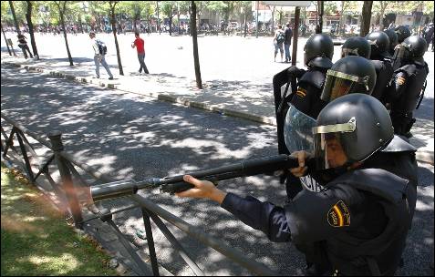 Un agente de la policía antidisturbios dispara una pelota de goma a los manifestantes - AFP