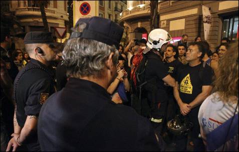 Varios de los funcionarios, entre ellos policías, bomberos o profesores, vigilados por miembros de la policia nacional, durante la manifestación que ha recorrido esta tarde-noche distintas zonas de la capital madrileña. EFE/Victor Lerena