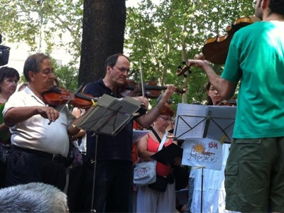 La 'Orquesta Solfónica', la banda del 15-M, interpreta música clásida en el Paseo del Prado - Foto: @letras15M