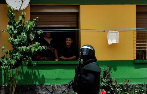 Dos vecinos observan a un guardia civil antidisturbios - REUTERS