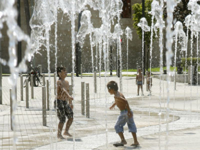 Varios niños juegan en una fuente de Bilbao para luchar contra las altas temperaturas de estos días.
