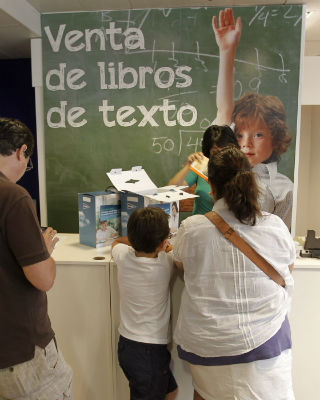 Una mujer espera ante el mostrador de una gran superficie de Madrid para hacerse con los libros de texto de su hijo.