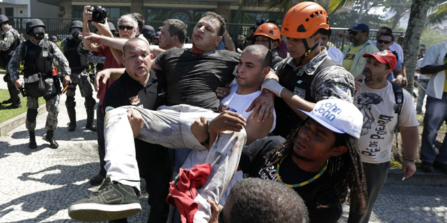 Los manifestantes portan a un herido de durante un enfrentamiento con los soldados de la Fuerza Nacional de Barra da Tijuca playa cerca del Hotel Windsor.-