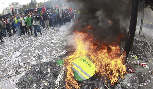 Los trabajadores de limpieza viaria y jardinería de Madrid queman sus uniformes frente al Ayuntamiento en protesta por los 1.144 despidos anunciados.