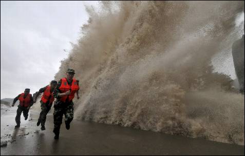 Soldados fronterizos corren, mientas una gran ola golpea la costa, bajo la influencia del tifón Fitow en Wenling, provincia de Zhejiang.