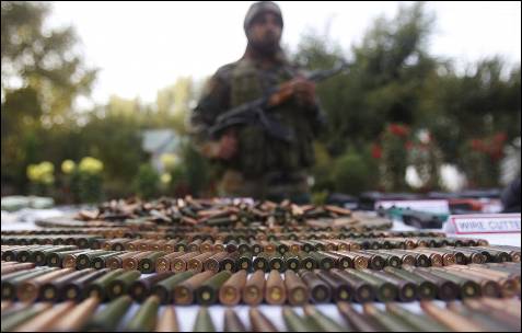 Un soldado del Ejército indio está detrás de una exhibición de armas y municiones incautadas en una guarnición en Srinagar.