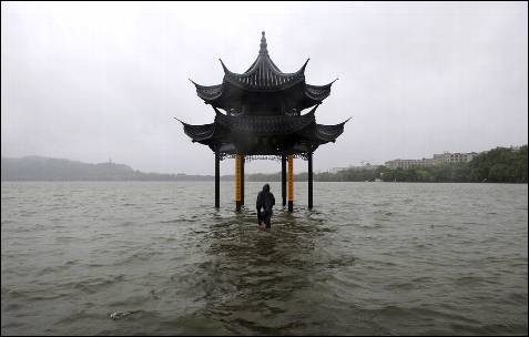 Un hombre camina hacia un pabellón inundado por el desbordamiento del lago Oeste después de que el tifón Fitow golpease Hangzhou, provincia de Zhejiang.