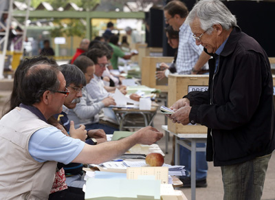 Un chileno recoge las papeletas para votar en una mesa electoral hoy, domingo 17 de noviembre.- Felipe Trueba (EFE)