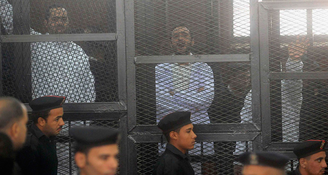 Los activistas políticos Ahmed Maher (d), Ahmed Douma (c) y Mohamed Adel, del Movimiento 6 de Abril, miran desde detrás de las rejas en la corte Abdeen, en El Cairo