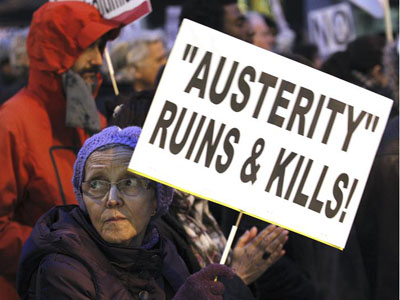 Una mujer porta una pancarta con el lema en inglés 'Austeridad arruina y mata¡', en la manifestación del colectivo Re-acciona en Madrid contra las políticas de la UE/EFE
