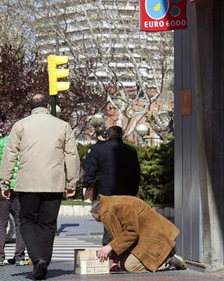 Un hombre pide limosna a la puertas de una entidad bancaria en Zaragoza.