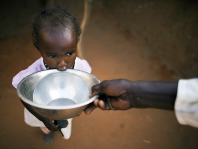 La joven Ismael Adam bebe agua de un cuenco en el refugio para desplazados de Abu Shouk en Darfur (Sudán). EFE/ Unamid Handout/Albert Gonzalez