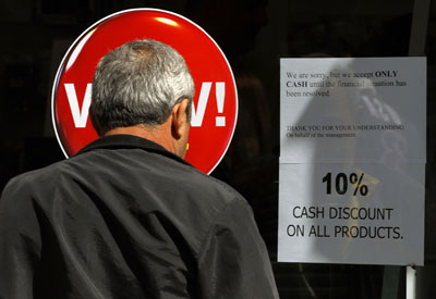 Un hombre lee el cartel en un comercio de Nicosa que avisa que sólo acepta pagos en efectivo.