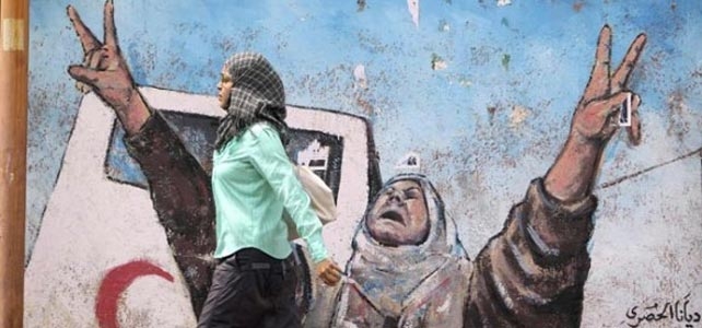 Una mujer pasa junto a un muro reinvidicativo en Gaza. REUTERS