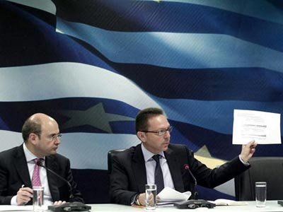 El ministro griego de Finanzas, Yannis Stournaras (d), muestra un papel a los periodistas durante una rueda de prensa ofrecida junto al ministro griego de Desarrollo, Kostis Hatzidakis (i), en el Ministerio de Finanzas de Atenas. -EFE