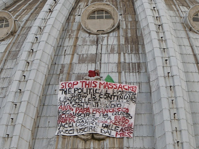 Ante la mirada de los turistas, el hombre ha desplegado un pancarta con la frase 'Stop a la masacre, no al euro'.
