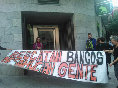 Activistas de Madrid despliegan una pancarta frente a la puetrta de la ofina de Bankia de la calle Pez.
