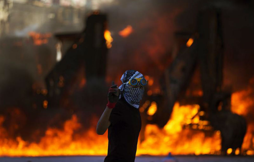 Un manifestante pasa delante de un vehículo incendiado durante un enfrentamiento contra la policía antidisturbios en la Plaza Taksim de Estambul.
