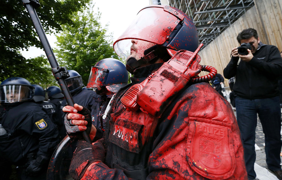 Un policía machado con pintura roja arrojada por los manifestantes en el cerco del movimientos Blockupu al BCE en Frankfurt, Alemania.