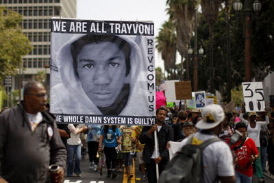 Varios manifestantes portan una pancarta con una fotografía de Trayvon Marti, en Los Angeles.- DAVID MCNEW (REUTERS)