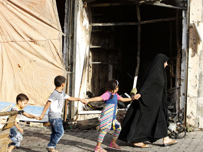 Una familia camina junto al lugar en el que explotó un coche bomba, en el barrio de Tobchi, Bagdad, el 21 de julio de 2013. REUTERS/Thaier al-Sudani