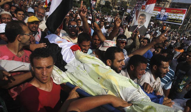 Seguidores del derrocado Mursi llevan el cuerpo de uno de los muertos en los alrededopres de la sede de la Guardia Republicana este lunes.