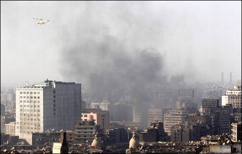 Un helicóptero militar sobrevuela las nubes de humo provocadas por las revueltas en El Cairo.