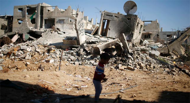 Un niño juega junto a las ruinas de la casa de su familia en Gaza.