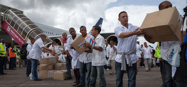 Los primeros miembros de un equipo de 165 mdicos cubanos y trabajadores de la salud descargan ellos mismos las cajas de medicamentos y material mdico de un avin.