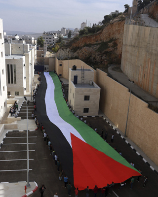Decenas de personas despliegan una bandera de 100 metros con motivo del décimo aniversario de la muerte de Yaser Arafat. EFE